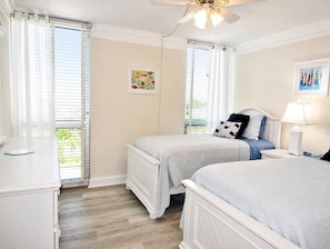 A bedroom with two beds, a ceiling fan, and a window with blinds. - Beachfront Vacation Rental With Full Gulf View (Longboat Key)
