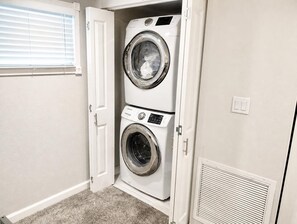 A laundry room with two stacked washers and dryers, a door, and a vent. - Gorgeous 3-bedroom beachfront unit at Club Longboat! (Longboat Key)