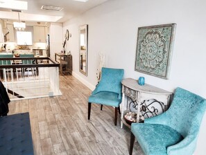A modern living room with a dining area, wooden flooring, and a large decorative mirror. - Gorgeous 3-bedroom beachfront unit at Club Longboat! (Longboat Key)