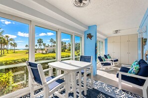 Ein sonnendurchflutetes Zimmer mit Blick auf einen Golfplatz, weißen Möbeln und einer blauen Akzentwand.