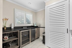 Eine moderne Küche mit schwarzem Arbeitsplatz, integriertem Backofen, Geschirrspüler und einem Fenster mit weißen Jalousien.