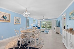 A spacious living area with a dining table, chairs, a chandelier, and artwork on the walls. - Stunning Updated Beachfront Rental on Longboat Key, Close to Ami, Shopping, Dining, and More! (Longboat Key)
