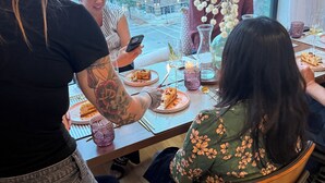 A group of people dining at a table with a view of a cityscape through large windows.