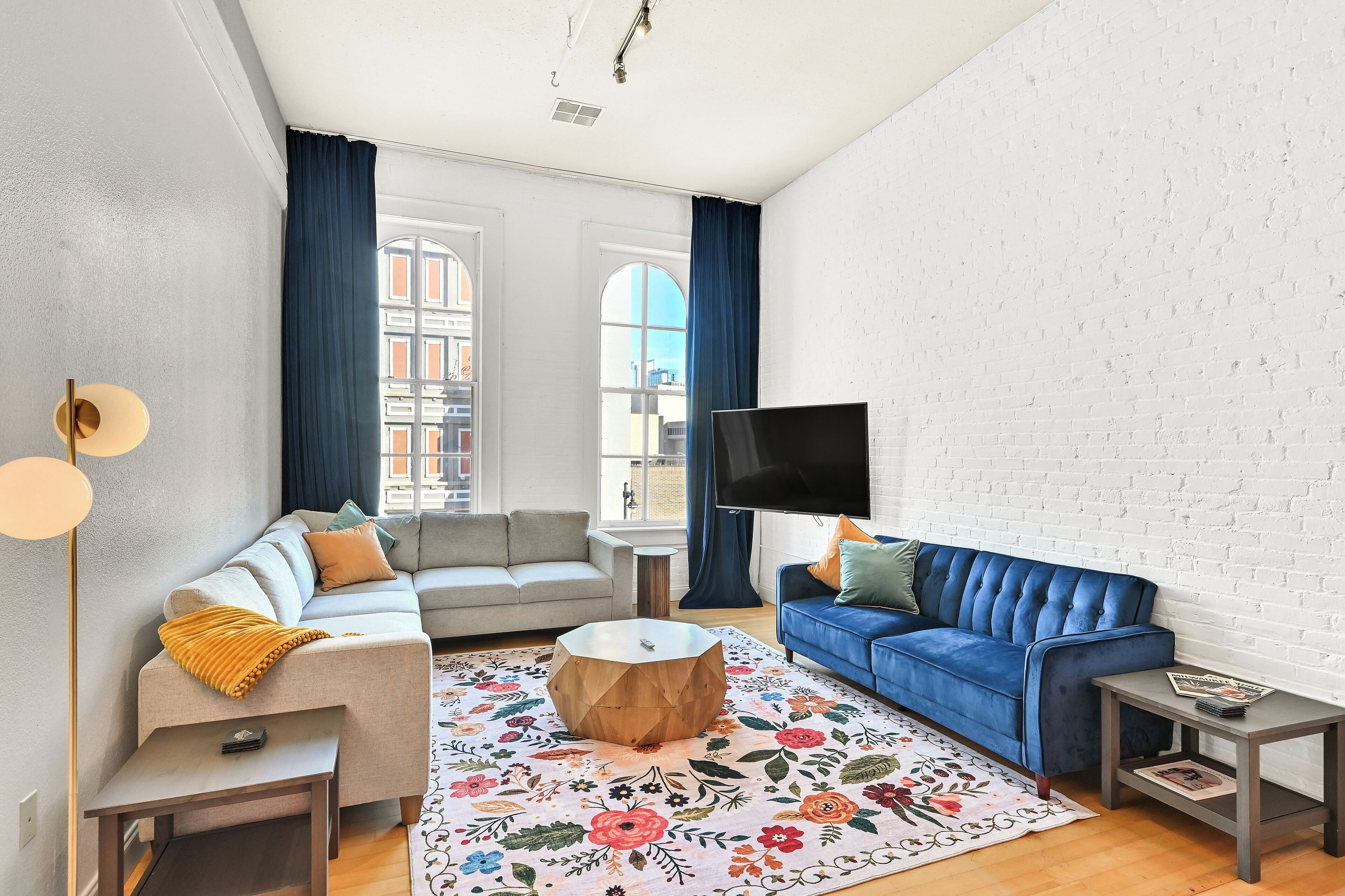 A living room with a sofa, a blue couch, a coffee table, and a flat-screen TV.