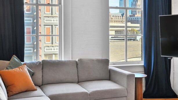 A modern living room with a grey sofa, a small side table, and a TV on a stand.