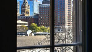 A view through a window of a cityscape with a prominent clock tower and modern buildings.