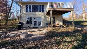 Une maison à deux étages dotée d’un balcon, d’un barbecue et d’un espace patio.