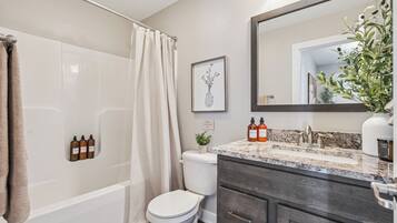 A bathroom with a shower, toilet, and vanity with a mirror.