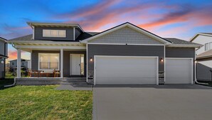 Ein zweistöckiges Haus mit Garage, überdachter Veranda und gepflegtem Rasen.