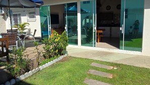 Uma casa moderna com um pátio, área de estar externa e uma porta de vidro que dá para o interior.