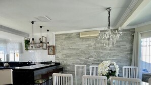 Cozinha moderna com ilha de mármore, cadeiras brancas e um lustre.