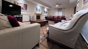 A living room with a flat-screen TV, two sofas, a coffee table, and ceiling fans.