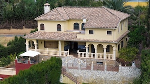 A two-story house with a tiled roof, a stone staircase, and a balcony.