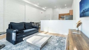 A modern living area with a sofa, coffee table, and a kitchen in the background. - Luxury Old City - The Heritage (Philadelphia)