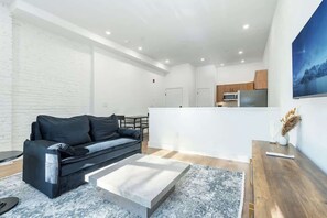 Ein modernes Wohnzimmer mit einer Couch, einem Couchtisch und einer Küche im Hintergrund.
