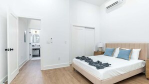 A bedroom with a bed, bedside table, and an air conditioning unit. - Luxury Old City - The Heritage (Philadelphia)
