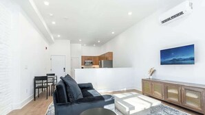 A modern living room with a sofa, a dining table, and a kitchen in the background. - Luxury Old City - The Heritage (Philadelphia)