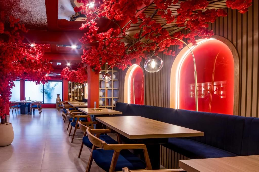 A restaurant interior with wooden tables, blue upholstered seating, and red floral decorations on the ceiling.