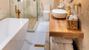 A modern bathroom with a large bathtub, a glass-enclosed shower, and a vanity with a mirror and sink. - Berthas Collection By EM Hotels (Cartagena)