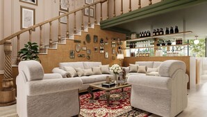 A spacious living room with a large sectional sofa, a coffee table, and a red patterned rug. A staircase with wooden balusters leads to an upper level. - Berthas Collection By EM Hotels (Cartagena)
