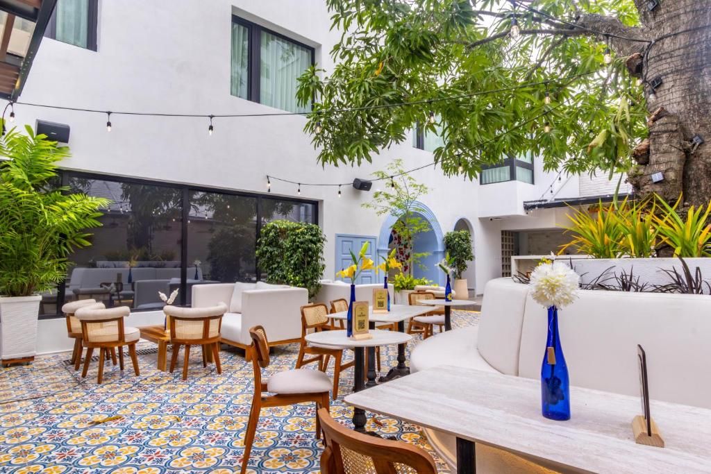 An outdoor seating area with tables and chairs, surrounded by potted plants and a tree.