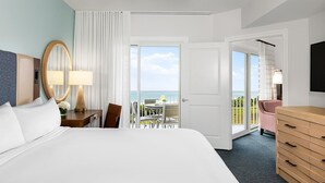 A hotel room with a large bed, a desk with a lamp, a chair, a dresser, and a balcony with a table and chairs. - Marriott's SurfWatch Resort 2 Bedroom/2 bath - Courtyard view (Hilton Head Island)