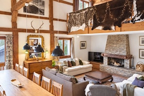 A rustic interior with exposed wooden beams, a stone fireplace, and a large fur hanging from the ceiling.