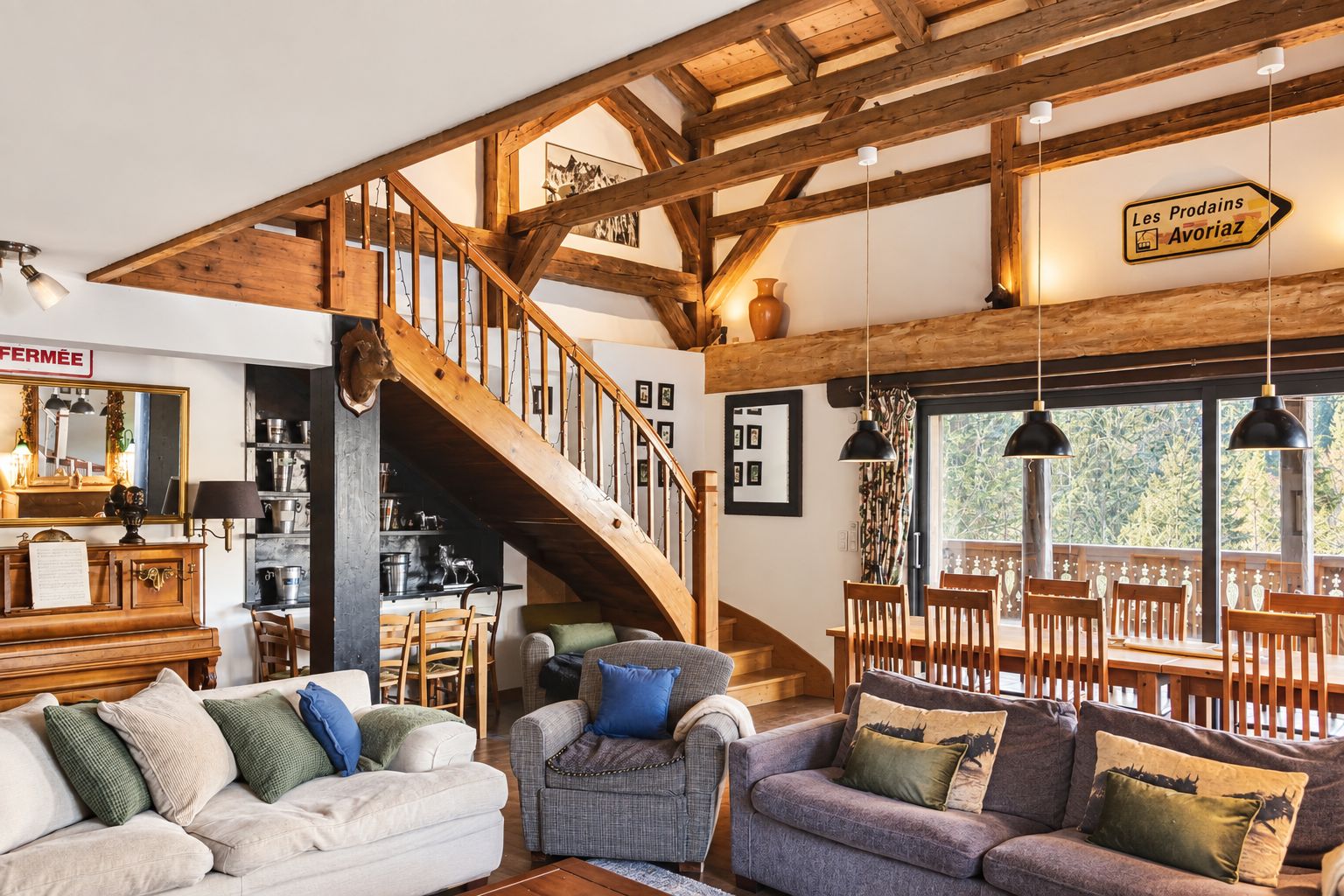 A rustic interior with exposed wooden beams, a staircase, and a dining area with wooden furniture.