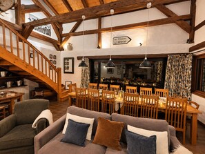 A dining area with wooden furniture, a staircase, and a sign indicating directions to Les Prodains and Avariaz.