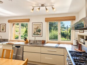 A modern kitchen with a large island, stainless steel appliances, and large windows offering a view of the outdoors.