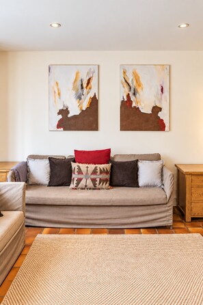 A living room with a sofa, two abstract paintings, and a wooden side table.