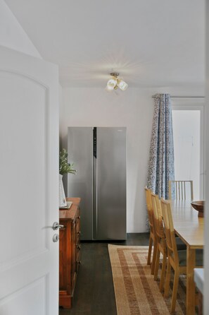 A kitchen with a stainless steel refrigerator, wooden cabinets, and a dining area with a table and chairs.
