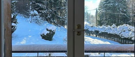 Vista a través de una puerta que muestra un paisaje nevado y una valla de madera.
