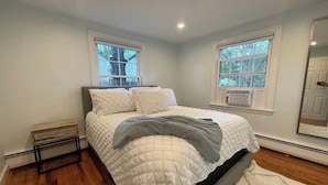 Una camera da letto con un letto, due finestre, un termosifone e uno specchio.