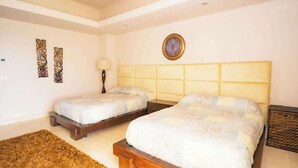 A bedroom with two beds, a brown rug, and decorative wall art. - Ocean Terrace 3 Habitaciones (Nuevo nayarit)