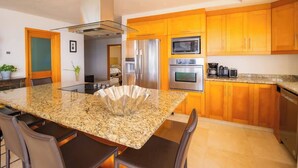 A modern kitchen with granite countertops, stainless steel appliances, and wooden cabinets. - Ocean Terrace 3 Habitaciones (Nuevo nayarit)