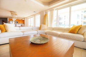 A modern living room with a sectional sofa, a wooden coffee table, and large windows. - Ocean Terrace 3 Habitaciones (Nuevo nayarit)