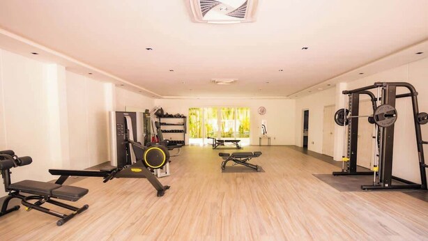 A spacious gym with various exercise equipment, a bench, and a window with a view. - Ocean Terrace 3 Habitaciones (Nuevo nayarit)