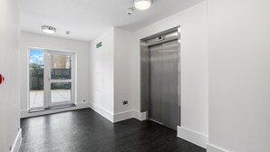 A hallway with a door leading to an outdoor area, a staircase, and an elevator. - Modern | City Stay | Walk to Station| Free Parking (Brighton and Hove)