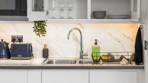 A kitchen with white cabinets, a microwave, a sink, and a plant. - Modern | City Stay | Walk to Station| Free Parking (Brighton and Hove)