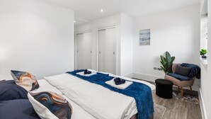 A modern hotel room with a large bed, a seating area, and a view of the hallway. - Modern | City Stay | Walk to Station| Free Parking (Brighton and Hove)