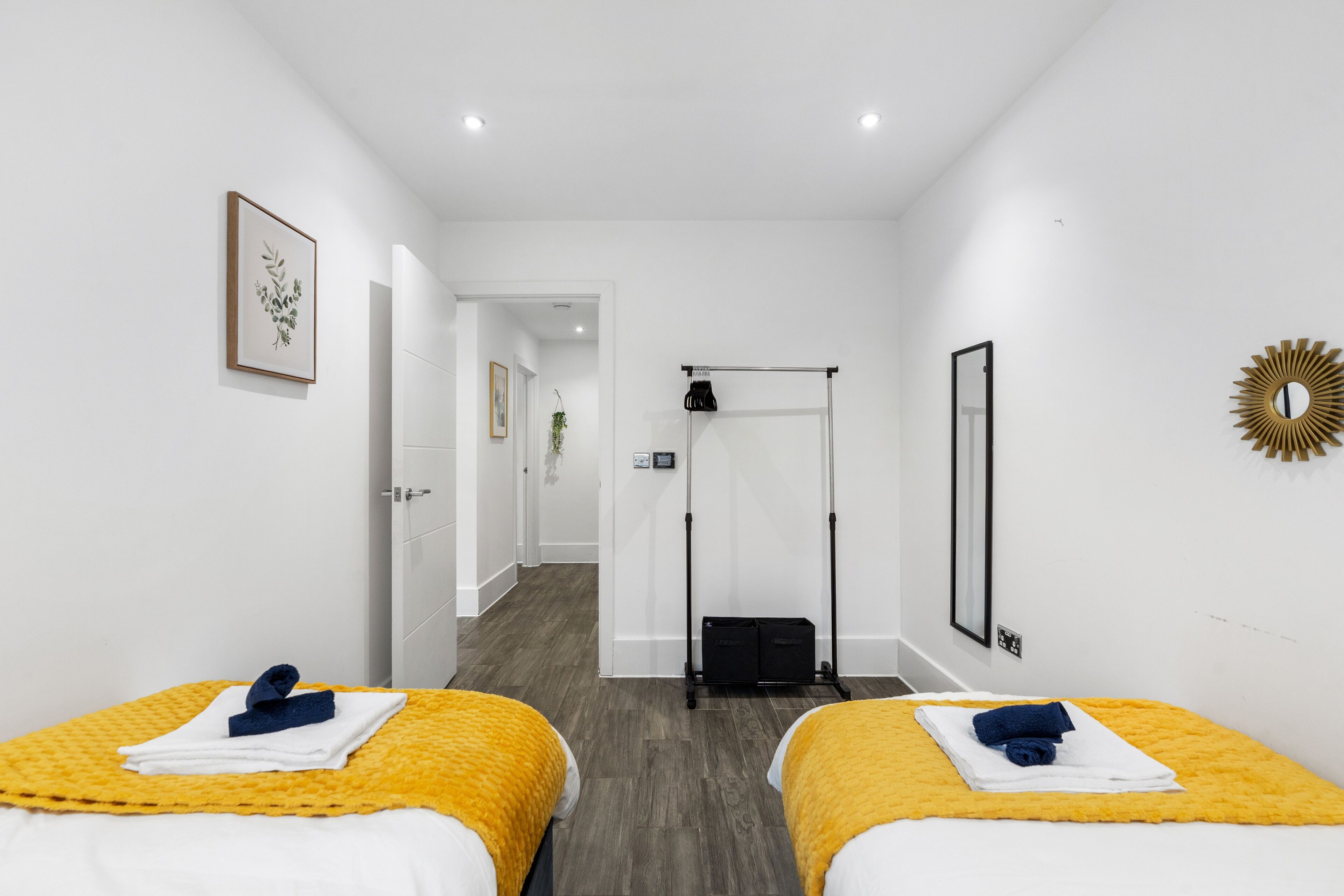 A hotel room with two beds, a workout station, and a framed botanical print on the wall.