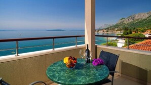A balcony with a table set for two, overlooking a coastal view with boats and a mountainous landscape. - Premium Double Room With Private Bathroom 1 (Gradac)