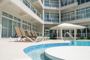 Ein Poolbereich mit Liegestühlen und einer überdachten Sitzgelegenheit.