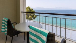 A balcony with a table and chairs, overlooking a turquoise sea and distant mountains. - Standard Double Room With Private Bathroom 1 (Gradac)
