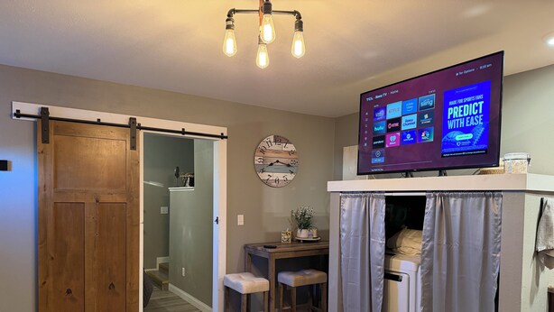 A living room with a TV, wooden door, and a small table with a chair. - Cozy 1-bedroom apartment in delightful Arlington  (Arlington)