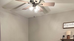 A bedroom with a bed, a ceiling fan, a bedside table with a lamp, and a wall-mounted shelf. - Cozy 1-bedroom apartment in delightful Arlington  (Arlington)