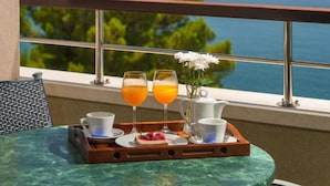 A balcony with a table set for breakfast, including two glasses of orange juice, a cup of coffee, and a teapot. - Panorama Suite With Private Bathroom (Gradac)