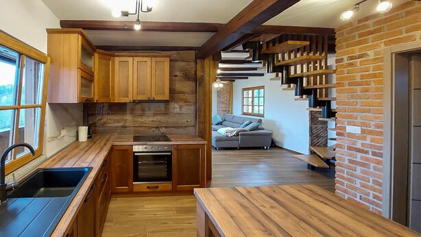 Una cocina con armarios de madera, un lavabo negro y un horno empotrado.