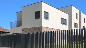 Een modern gebouw met twee verdiepingen, een plat dak, een balkon op de tweede verdieping en een gevel van baksteen.